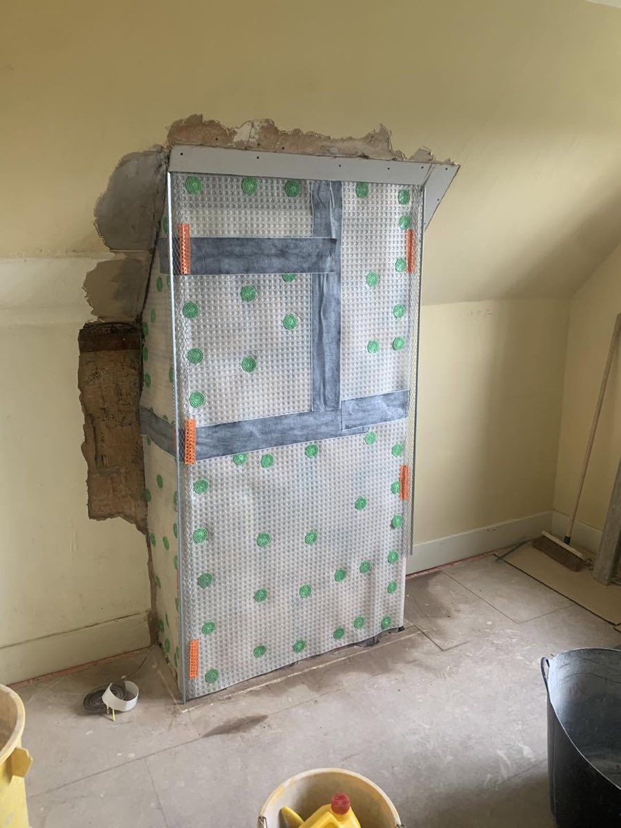 A chimney breast faced with damp-proof membrane over a metal mesh backing during remedial works